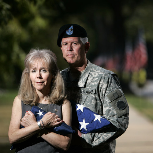 Carol and Mark Graham holding sons' memorial flags.